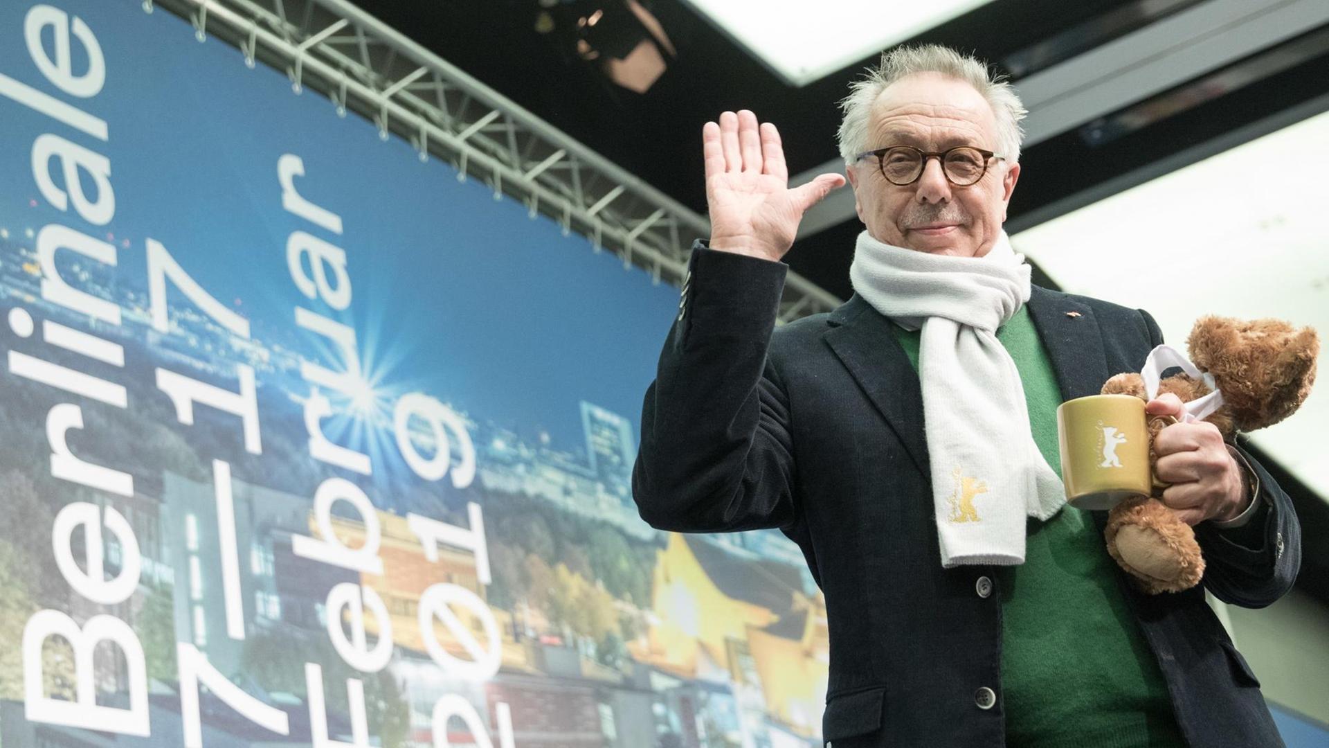 Dieter Kosslick steht vor einem Werbeplakat des Festivals und winkt freundlich in die Kamera. Dieter Kosslick steht vor einem Werbeplakat des Festivals und winkt freundlich in die Kamera.