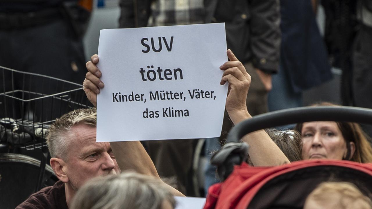 Ein Teilnehmer der Mahnwache, bei der der Verkehrstoten gedacht wird, stehen mit einem Schild mit der Aufschrift "SUV töten Kinder, Mütter, Väter, das Klima" an der Stelle, an der am Freitag (06.09.2019) vier Menschen bei einem Verkehrsunfall gestorben waren.