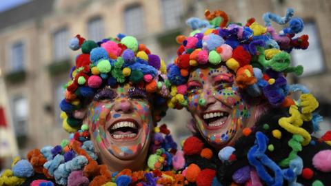 Zwei bunt geschmückte Karnevalistinnen feiern auf dem Düsseldorfer Rathausplatz das Hoppeditz-Erwachen.