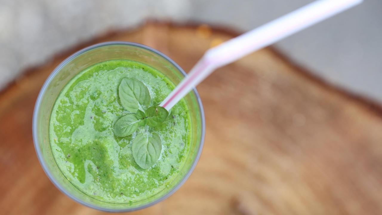 Ein grüner Smoothie in einem Glas mit Trinkhalm. Ein grüner Smoothie in einem Glas mit Trinkhalm.