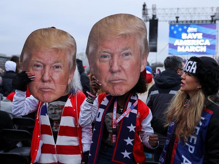 Mehrere Protestierende mit Trump-Masken stehen nahe dem Weißen Haus.