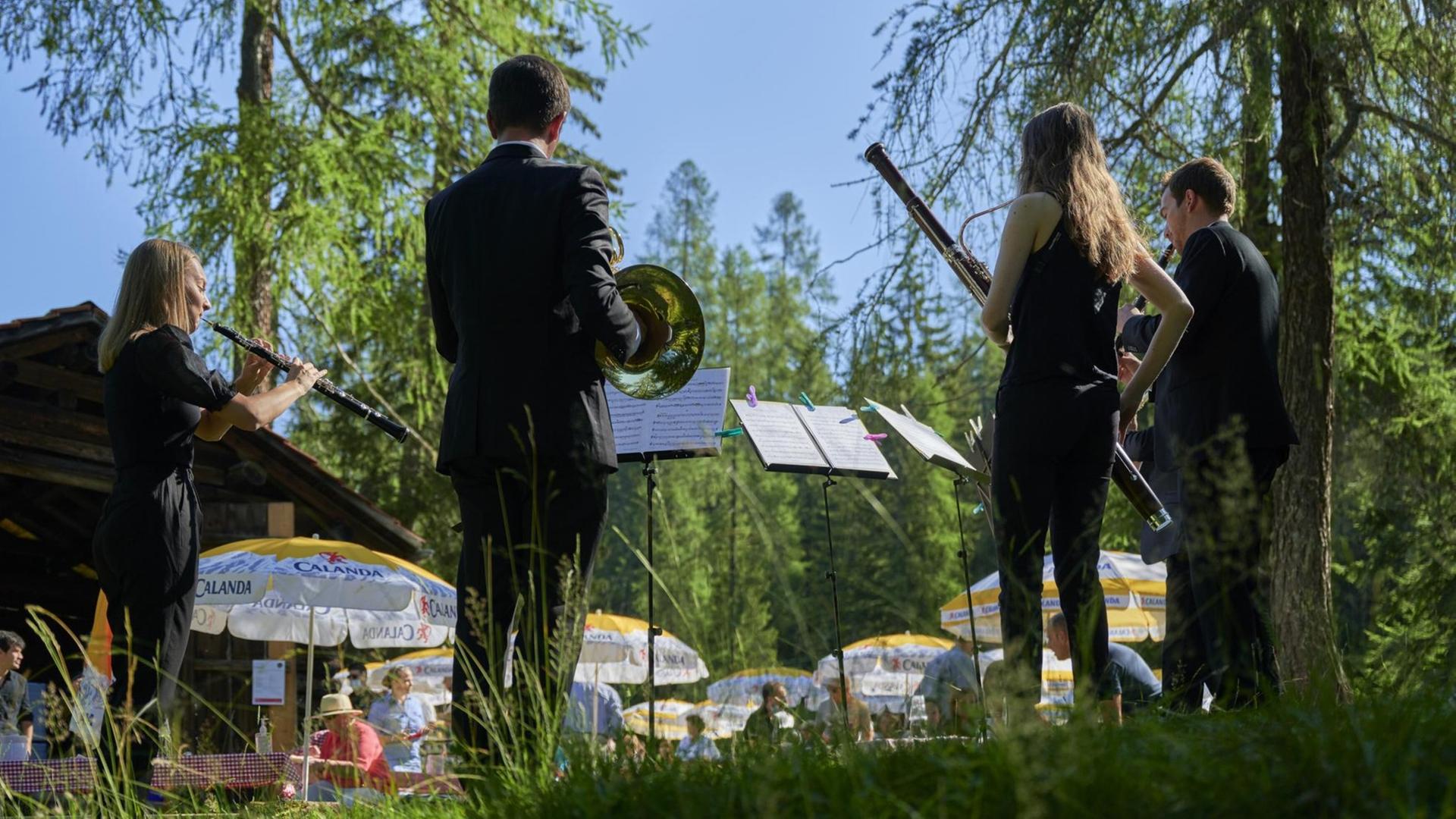 Musikerinnen und Musiker stehen beim Davos Festival 2020 unter Bäumen vor Publikum auf einer Wiese. Musikerinnen und Musiker stehen beim Davos Festival 2020 unter Bäumen vor Publikum auf einer Wiese.