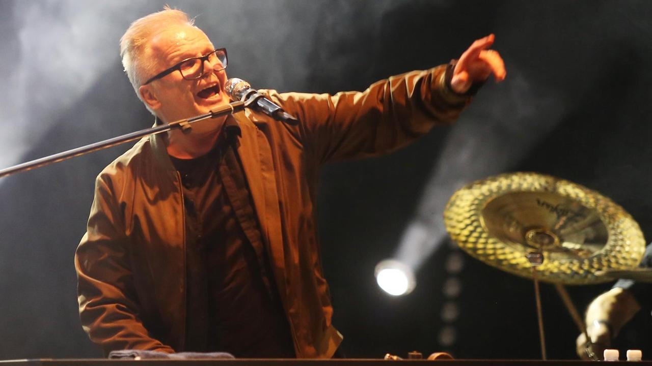 Herbert Grönemeyer singt auf der Bühne des Musikfestivals "Jamel rockt den Förster" in ein Mikrofon und hebt dabei den linken Arm.