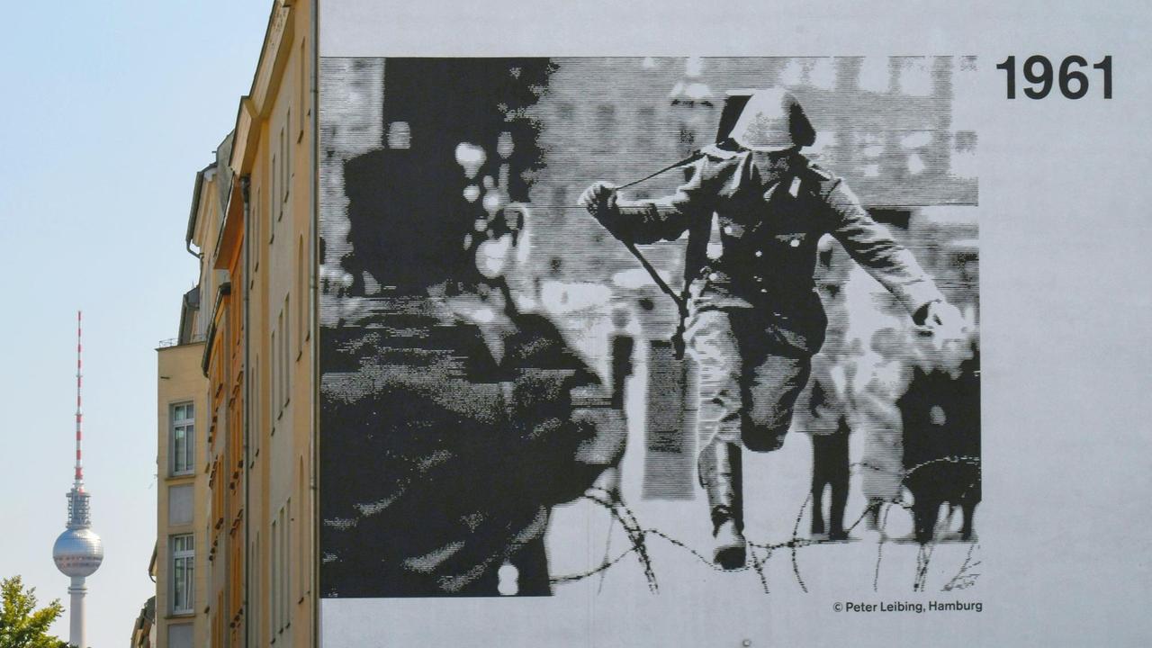 Abbildung des legendären Fotos von Peter Leibing an einer Hauswand in der Bernauer Strasse: Der Soldat Hans Conrad Schumann springt 1961 über den Stacheldraht. Abbildung des legendären Fotos von Peter Leibing an einer Hauswand in der Bernauer Strasse: Der Soldat Hans Conrad Schumann springt 1961 über den Stacheldraht.