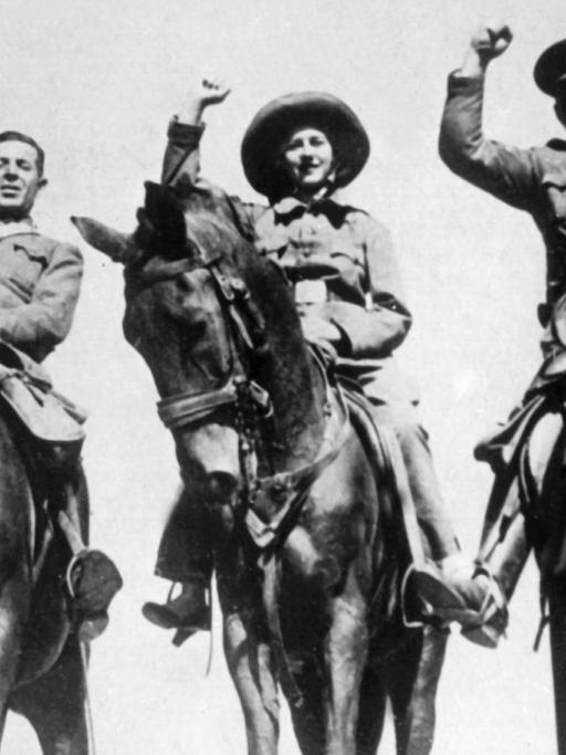 Rotspanische Kavalleristen kehren nach einem erfolgreichen Aufklärungsritt in ihre Stellung zurück (1936). Auf den drei Pferden sitzen zwei Männer und eine Frau.