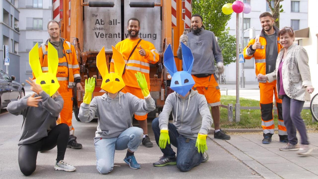 Drei Personen mit Hasenmasken, hinter ihnen stehen die Männer von der Müllabfuhr. Drei Personen mit Hasenmasken, hinter ihnen stehen die Männer von der Müllabfuhr.