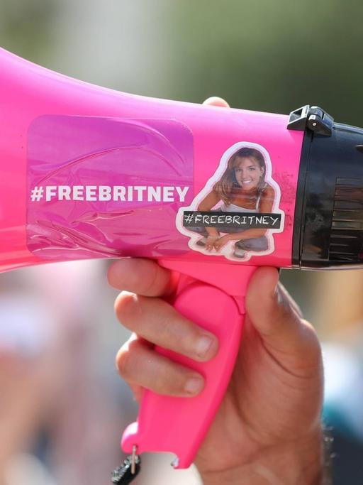 Zwei Menschen sprechen in ein rosa Megaphon, auf dem "Free Britney" steht.