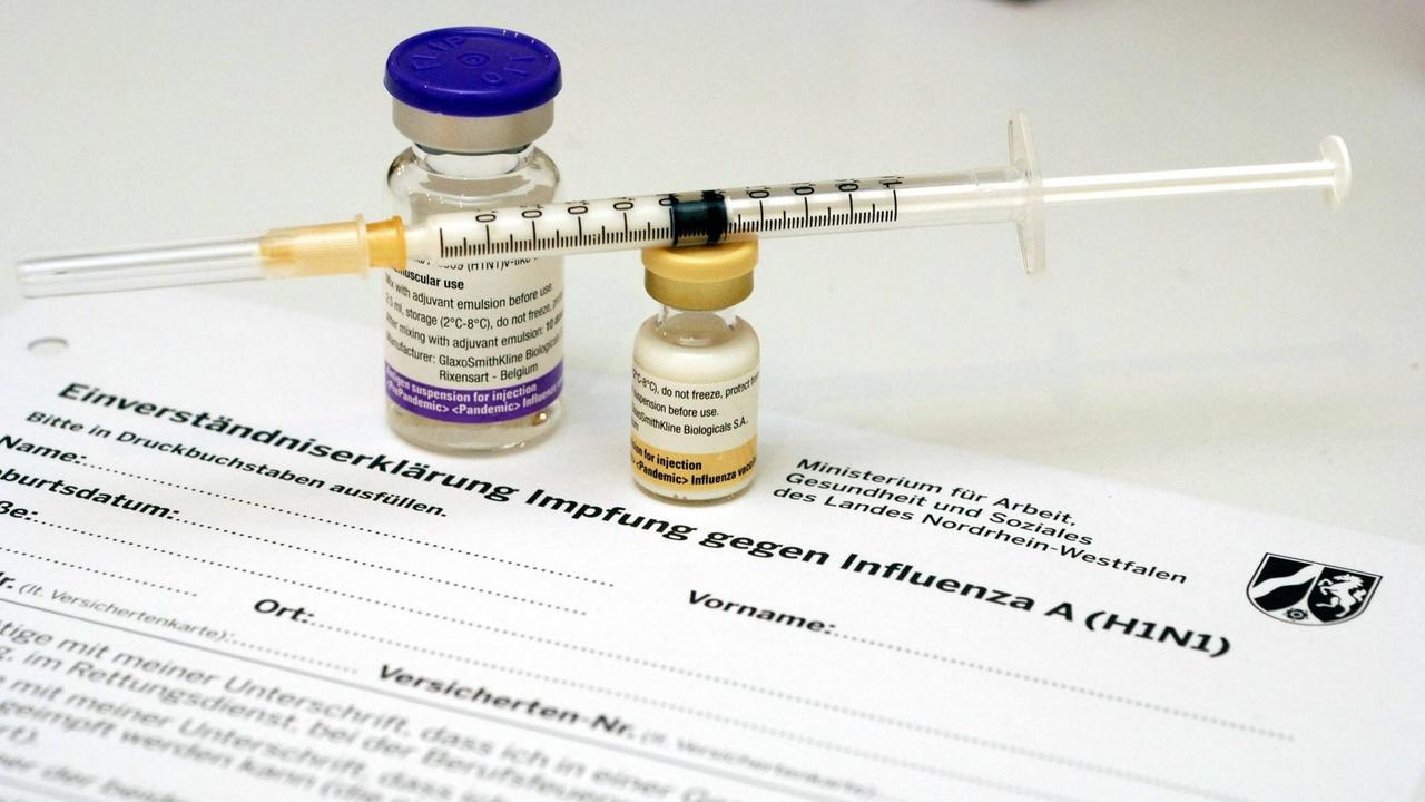 Glasdöschen mit dem Impfstoff Pandemrix und Impfspritze stehen auf einem Formular mit einer Impf-Einverständniserklärung Glasdöschen mit dem Impfstoff Pandemrix und Impfspritze stehen auf einem Formular mit einer Impf-Einverständniserklärung