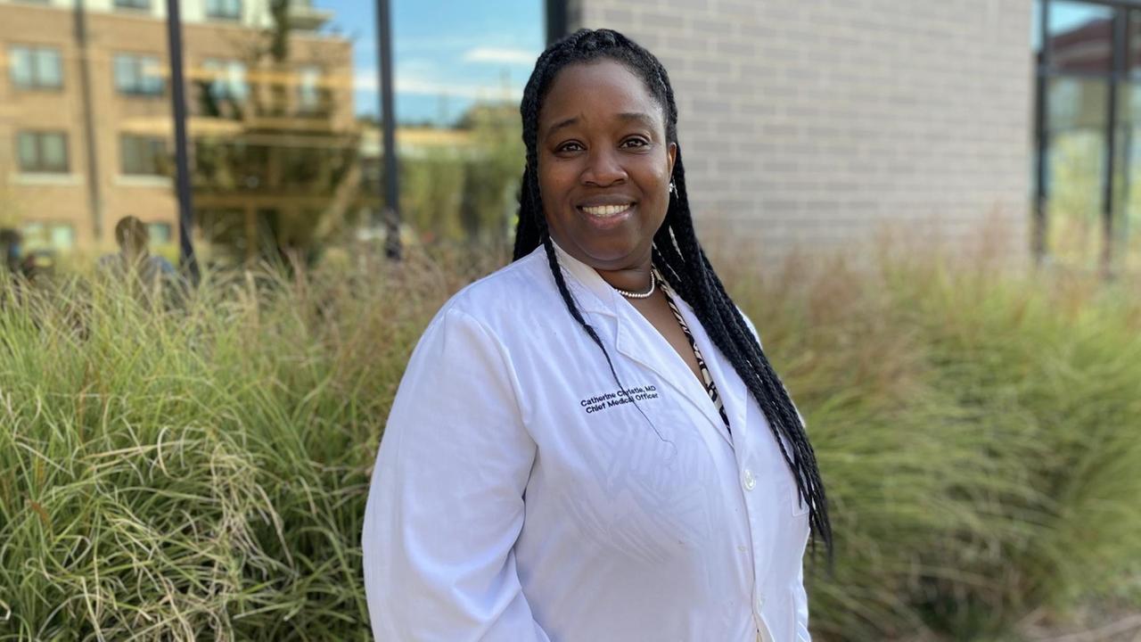 Dr. Catherine Christie ist die medizinische Direktorin von Mercy Care in Atlanta. Sieht steht im weißen Kittel draußen vor dem Gesundheitszentrum.