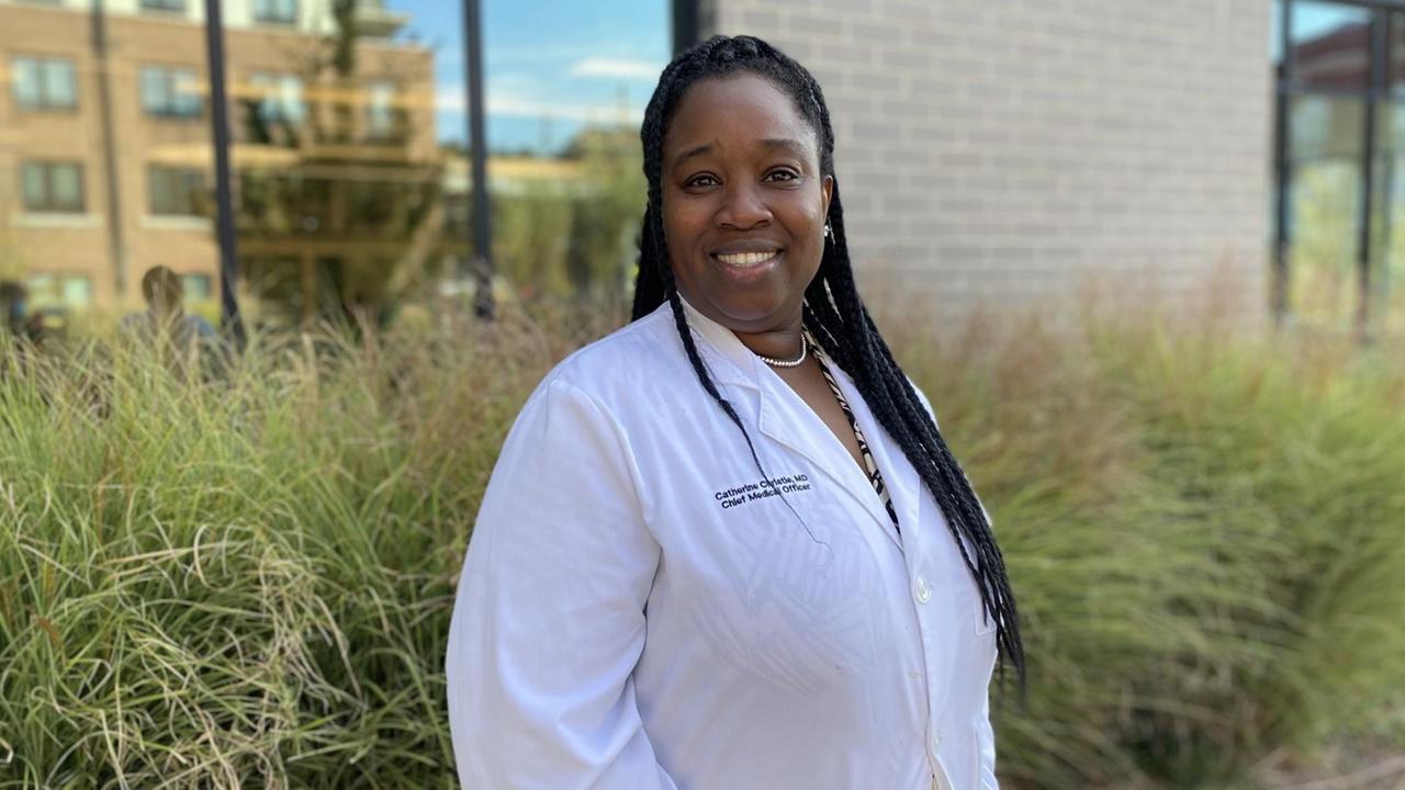 Dr. Catherine Christie ist die medizinische Direktorin von Mercy Care in Atlanta. Sieht steht im weißen Kittel draußen vor dem Gesundheitszentrum. Dr. Catherine Christie ist die medizinische Direktorin von Mercy Care in Atlanta. Sieht steht im weißen Kittel draußen vor dem Gesundheitszentrum.