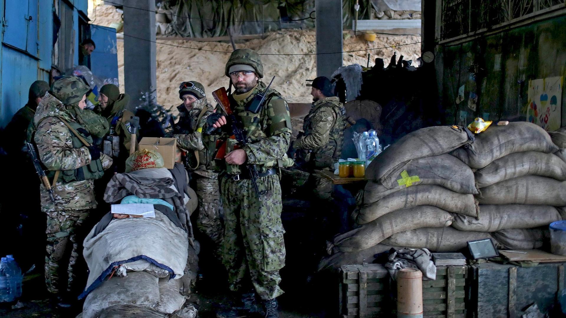 Eine Gruppe von ukrainischen Soldaten steht bewaffnet und mit Sandsäcken gesichert unter einer Brücke. Eine Gruppe von ukrainischen Soldaten steht bewaffnet und mit Sandsäcken gesichert unter einer Brücke.