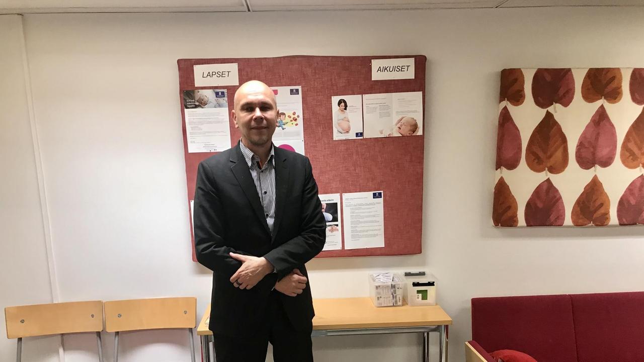 Ein kahlköpfiger junger Mann mit Anzug und verschränkten Armen steht in einem Büro. Ein kahlköpfiger junger Mann mit Anzug und verschränkten Armen steht in einem Büro.