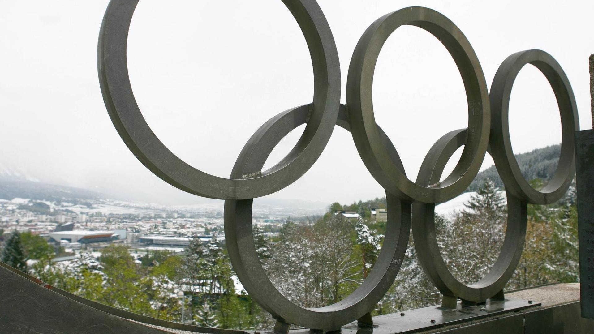 Großes Olympia-Logo aus Metall, im Hintergrund Stadt Innsbruck in Österreich Großes Olympia-Logo aus Metall, im Hintergrund Stadt Innsbruck in Österreich