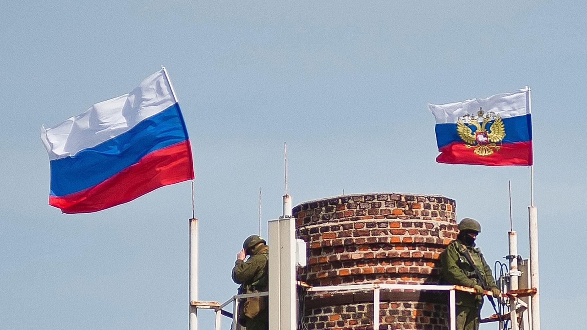 Bewaffnete unter der russischen Fahnen auf einem Schornstein in der Nähe des Marine-Hauptquartiers in Sewastopol Bewaffnete unter der russischen Fahnen auf einem Schornstein in der Nähe des Marine-Hauptquartiers in Sewastopol
