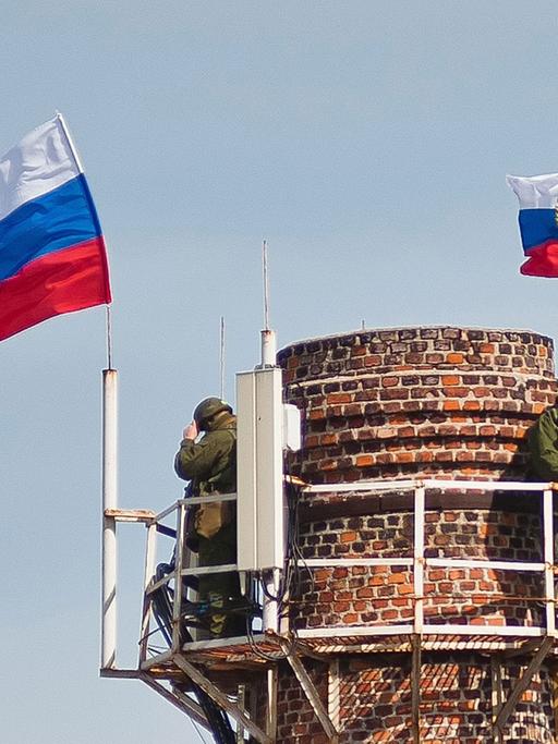Bewaffnete unter der russischen Fahnen auf einem Schornstein in der Nähe des Marine-Hauptquartiers in Sewastopol
