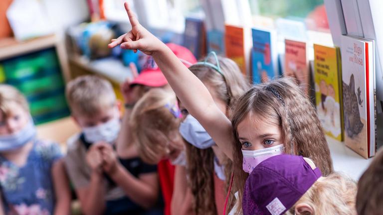 Schulanfängerin Ida meldet sich mit Mund-Nasen-Schutzmaske in der ersten Unterrichtsstunde der Klasse 1b in der Grundschule "Werner Lindemann". 
