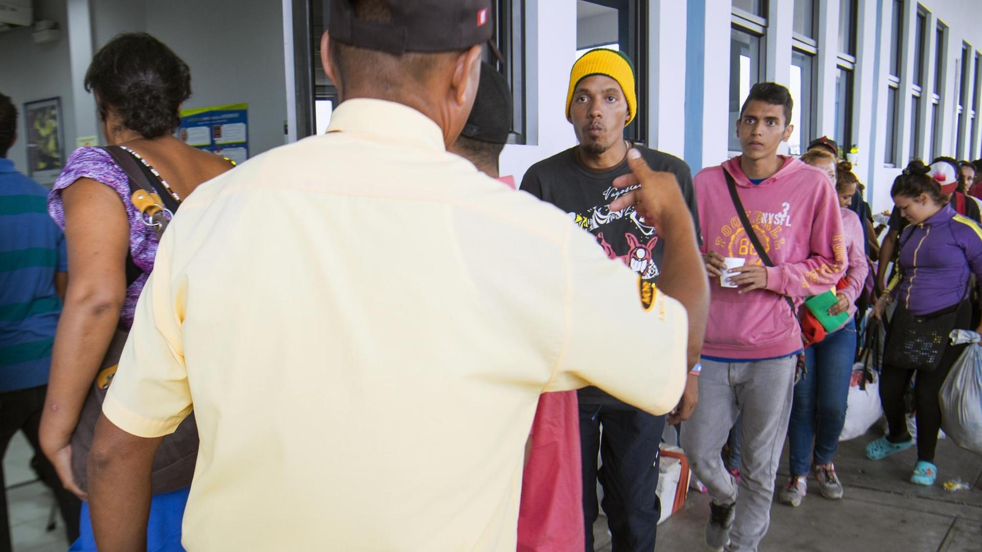 Flüchtlinge aus Venezuela stehen an der Grenze zu Peru in einer Schlange, um einen Asylantrag stellen zu können. Ein peruanischer Polizist winkt sie weiter. Flüchtlinge aus Venezuela stehen an der Grenze zu Peru in einer Schlange, um einen Asylantrag stellen zu können. Ein peruanischer Polizist winkt sie weiter.