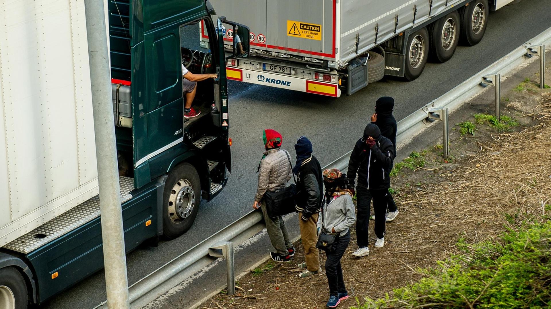 Flüchtlinge sprechen mit einem Lkw-Fahrer Flüchtlinge sprechen mit einem Lkw-Fahrer
