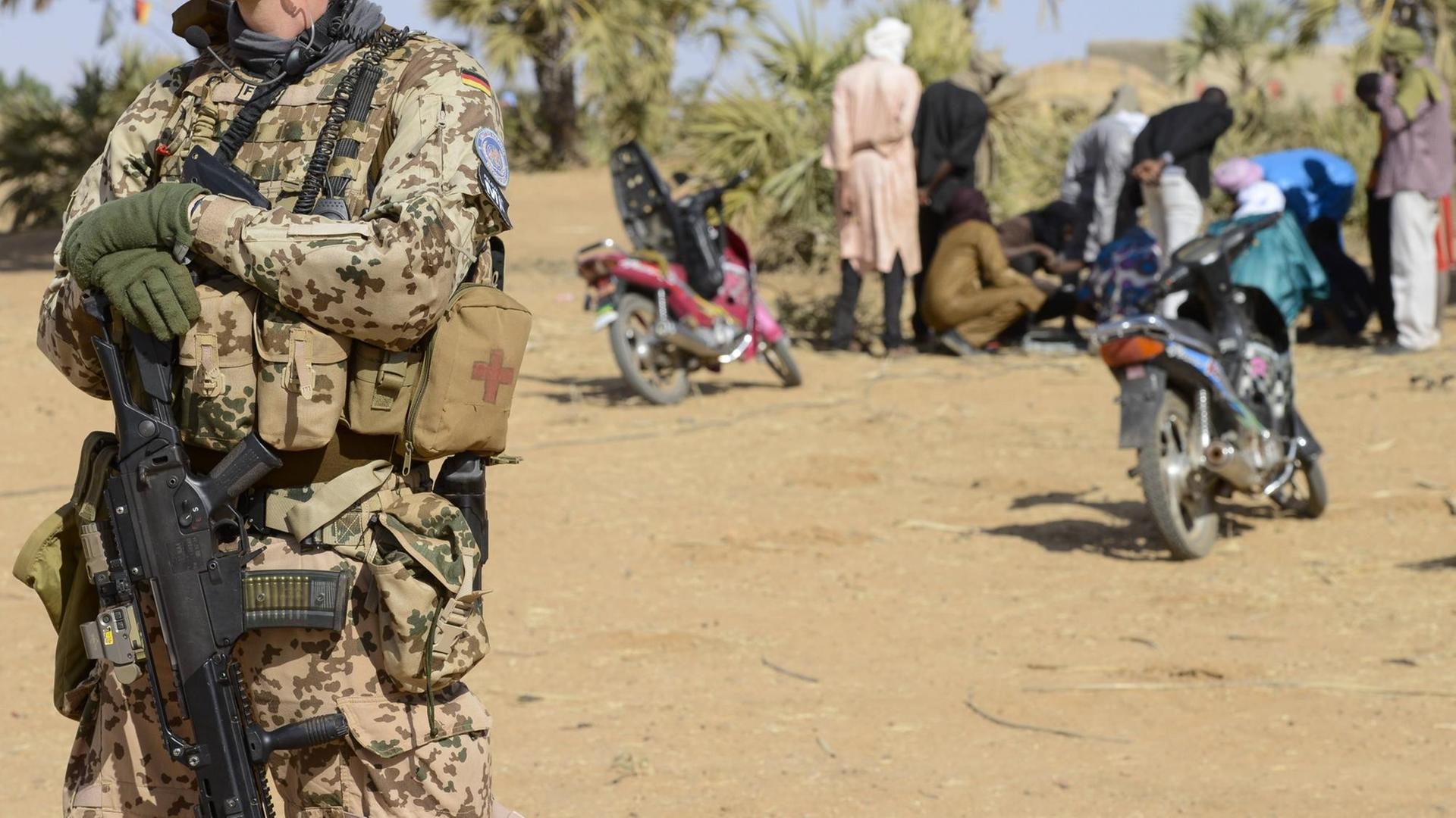 Ein deutscher Soldat der UN-Mission in Mali, im Hintergrund Einheimische Ein deutscher Soldat der UN-Mission in Mali, im Hintergrund Einheimische