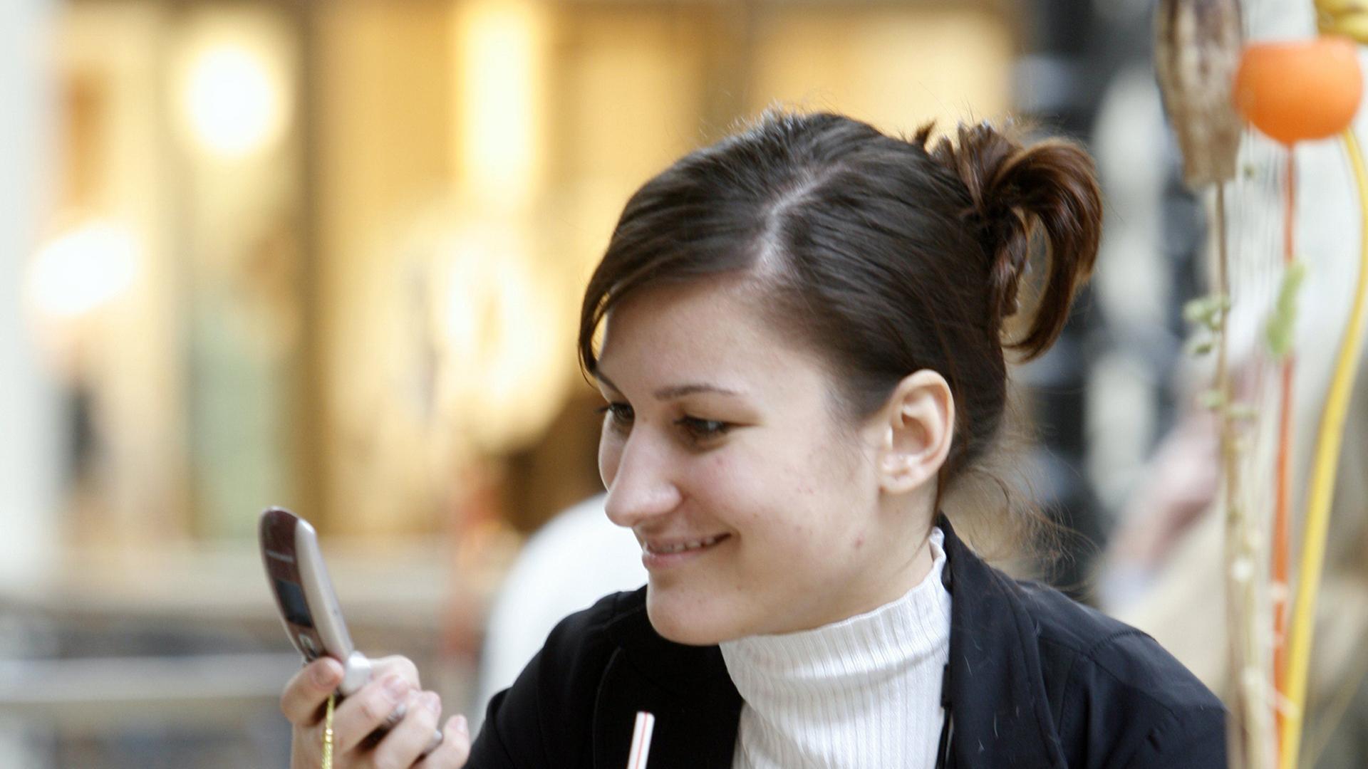 Eine junge Frau liest etwas auf ihrem Smartphone.