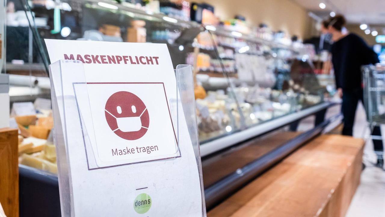 Schild mit Hinweis zur Maskenpflicht in einem Supermarkt. Schild mit Hinweis zur Maskenpflicht in einem Supermarkt.