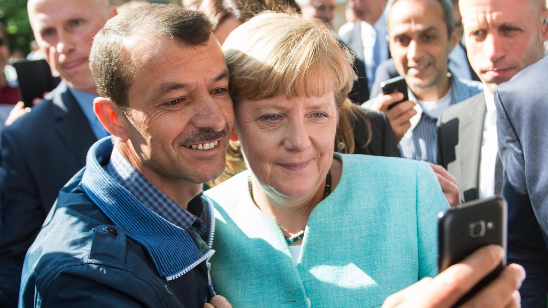 Bundeskanzlerin Angela Merkel (CDU) lässt sich am 10.09.2015 nach dem Besuch einer Erstaufnahmeeinrichtung für Asylbewerber der Arbeiterwohlfahrt (AWO) und der Außenstelle des Bundesamtes für Migration und Flüchtlinge in Berlin-Spandau für ein Selfie zusammen mit einem Flüchtling fotografieren. Bundeskanzlerin Angela Merkel (CDU) lässt sich am 10.09.2015 nach dem Besuch einer Erstaufnahmeeinrichtung für Asylbewerber der Arbeiterwohlfahrt (AWO) und der Außenstelle des Bundesamtes für Migration und Flüchtlinge in Berlin-Spandau für ein Selfie zusammen mit einem Flüchtling fotografieren.