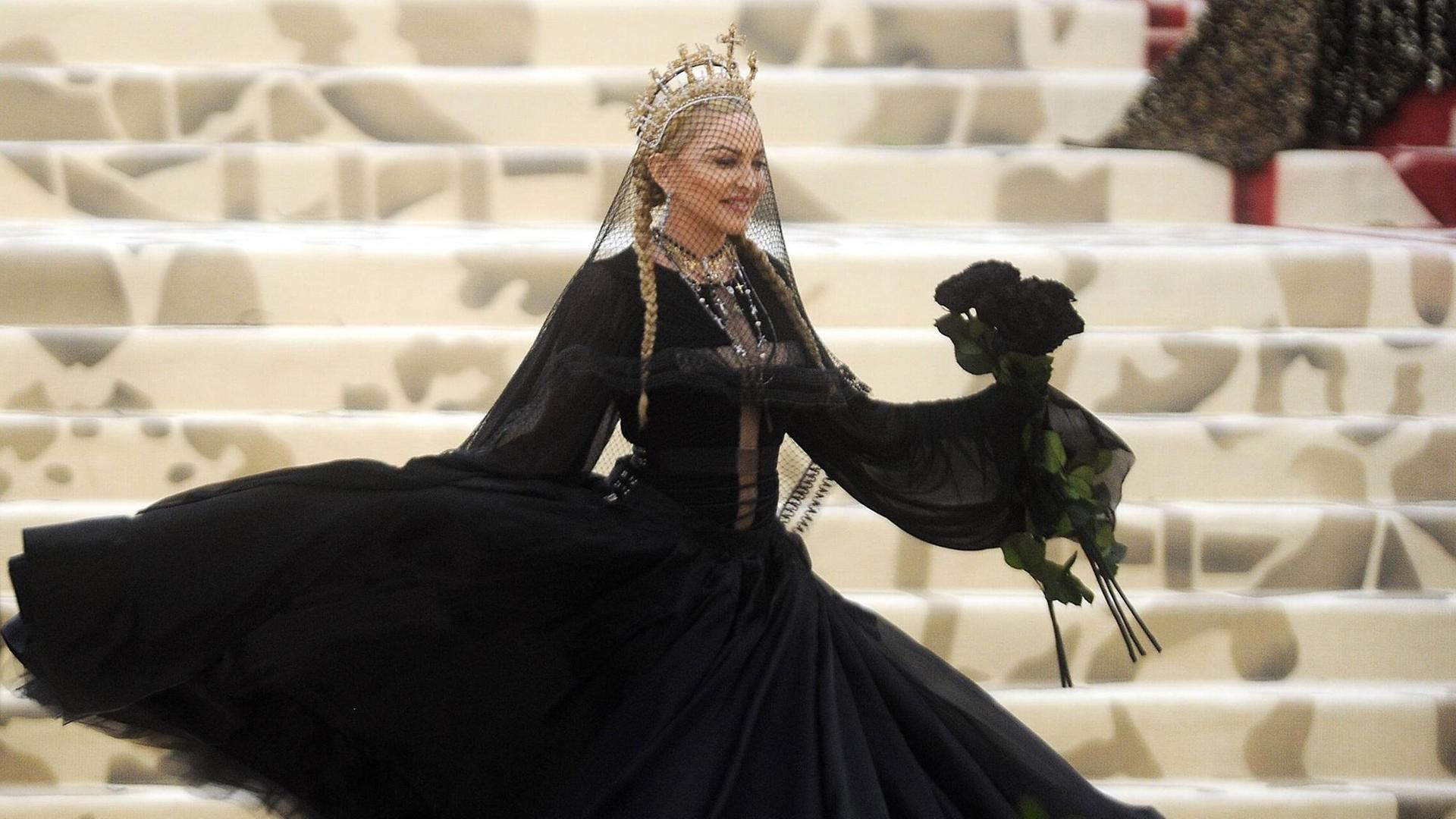 Madonna bei der Ausstellungseröffnung von "Heavenly Bodies" im New Yorker Metropolitan Museum am 7. Mai 2018 - sie trägt ein prächtiges schwarzes Kleid und eine goldene Krone, die mit Kreuzen verziert ist Madonna bei der Ausstellungseröffnung von "Heavenly Bodies" im New Yorker Metropolitan Museum am 7. Mai 2018 - sie trägt ein prächtiges schwarzes Kleid und eine goldene Krone, die mit Kreuzen verziert ist
