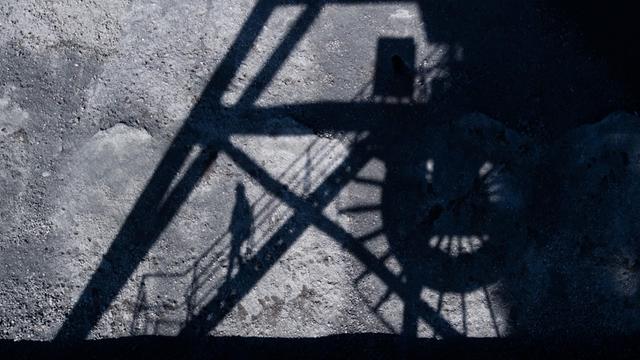 Steinkohle lagert im Kohlehafen vom Kohlekraftwerk Mehrum im Landkreis Peine, als der Schatten eines Mitarbeiters auf einer Brücke auf die Kohle fällt.