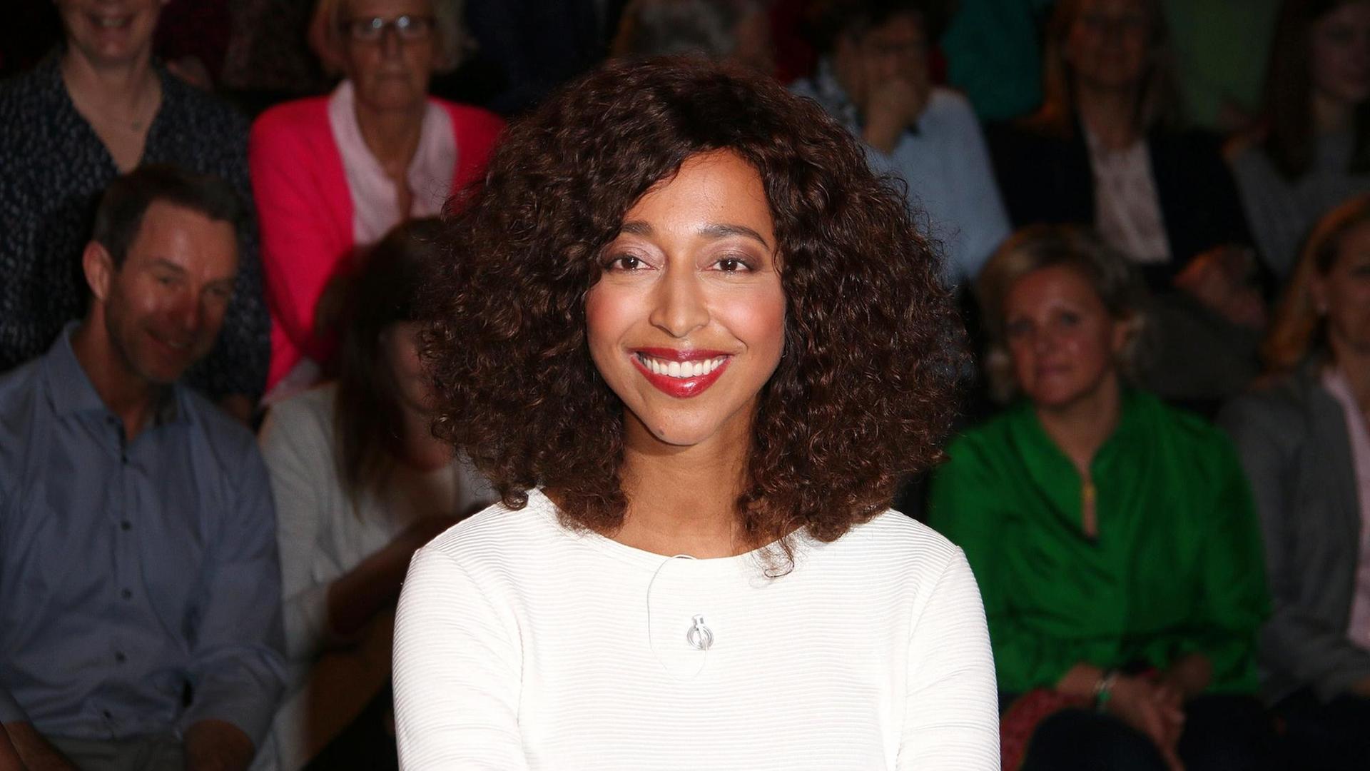 Melanie Raabe, dunkle, schulterlange Locken, braune Augen, trägt ein weißes Oberteil und schaut lächelnd in die Kamera. Melanie Raabe, dunkle, schulterlange Locken, braune Augen, trägt ein weißes Oberteil und schaut lächelnd in die Kamera.