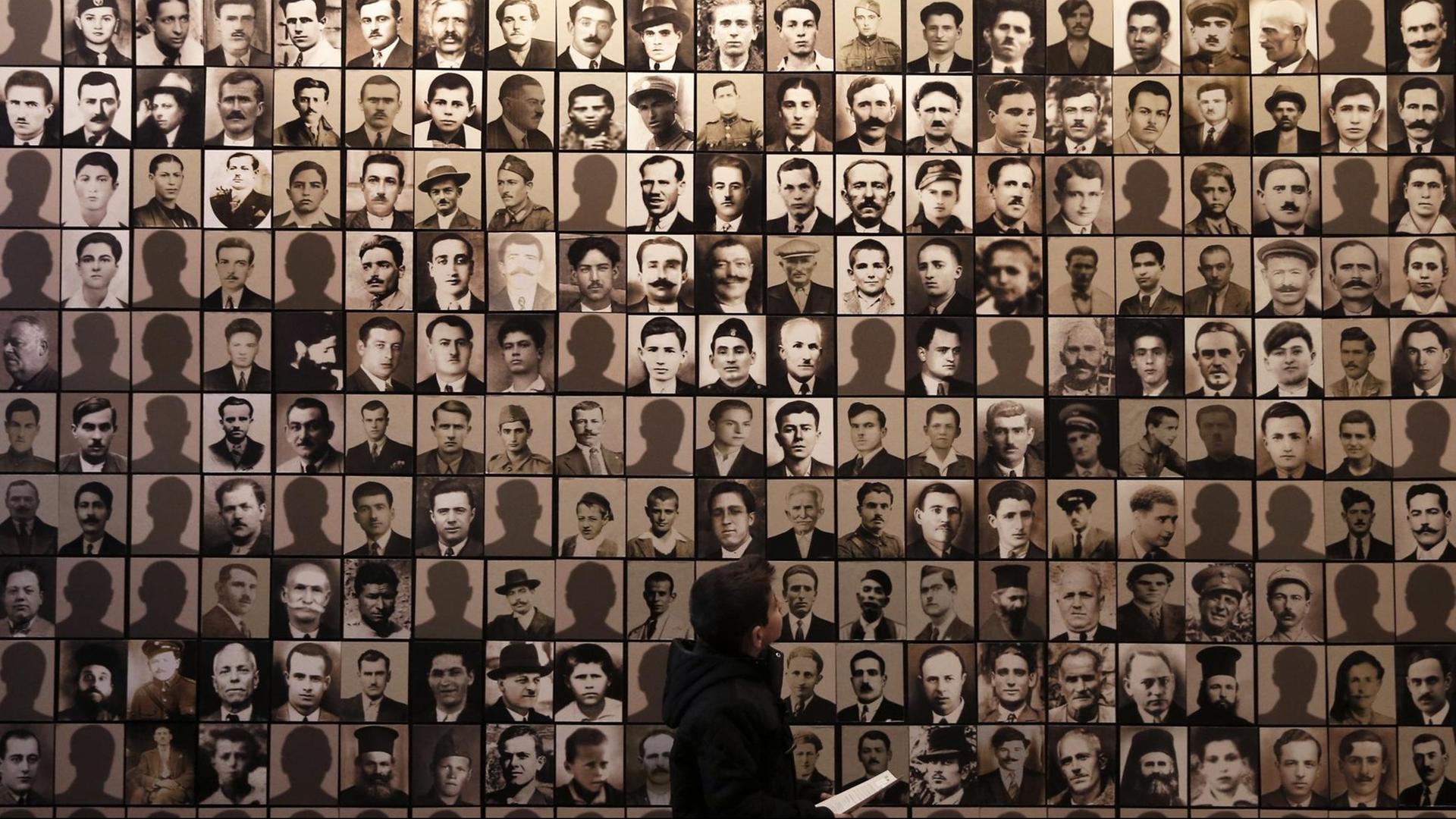 Ein Junge betrachtet am 21.3.2015 im Holocaust-Museum der griechischen Stadt Kalavryta die Porträts von Opfern des Massakers, das Wehrmachtssoldaten dort am 13. Dezember 1943 verübt haben.