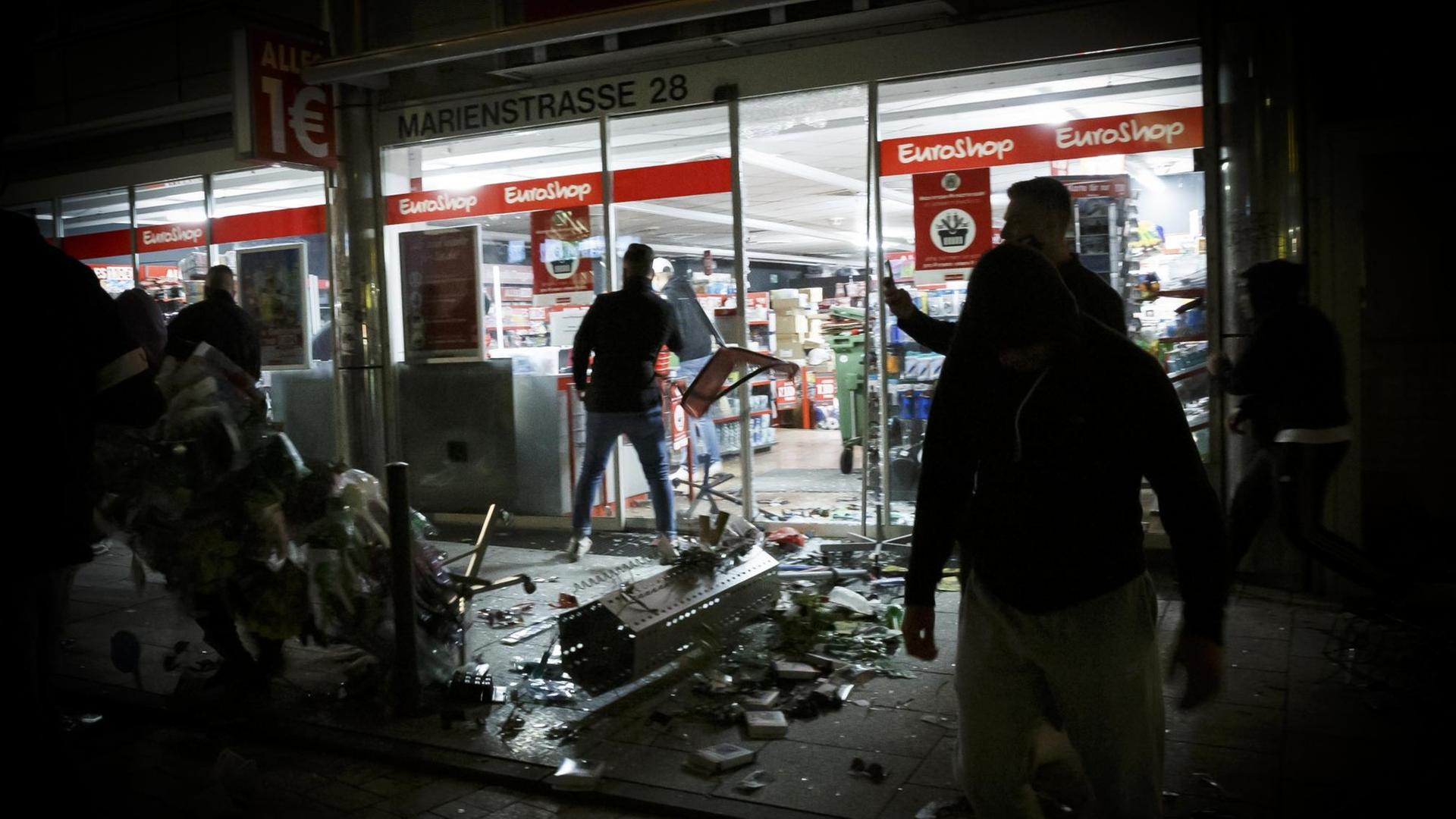 Menschen stehen vor einem geplünderten Geschäft in der Stuttgarter Marienstraße. Menschen stehen vor einem geplünderten Geschäft in der Stuttgarter Marienstraße.