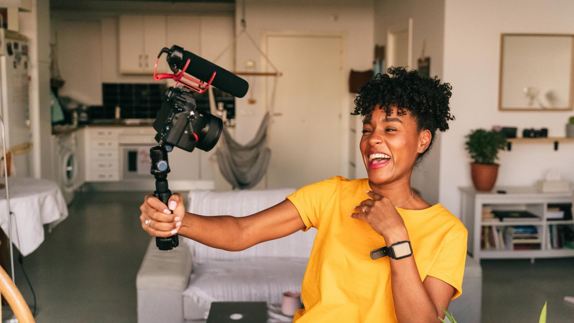 Fröhliche junge Bloggerin, die Videos aufnimmt, während sie zu Hause Inhalte für soziale Netzwerke vorbereitet. Fröhliche junge Bloggerin, die Videos aufnimmt, während sie zu Hause Inhalte für soziale Netzwerke vorbereitet.
