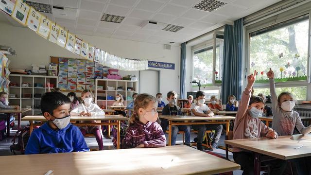 Kinder einer Grundschulklasse sitzen während der Corona-Pandmie mit Mundnase-Masken im Klassenzimmer