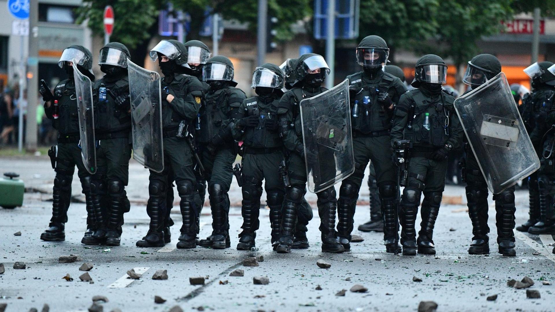 Polizisten stehen in St. Pauli in Hamburg vor Steinbrocken und Glasscherben.