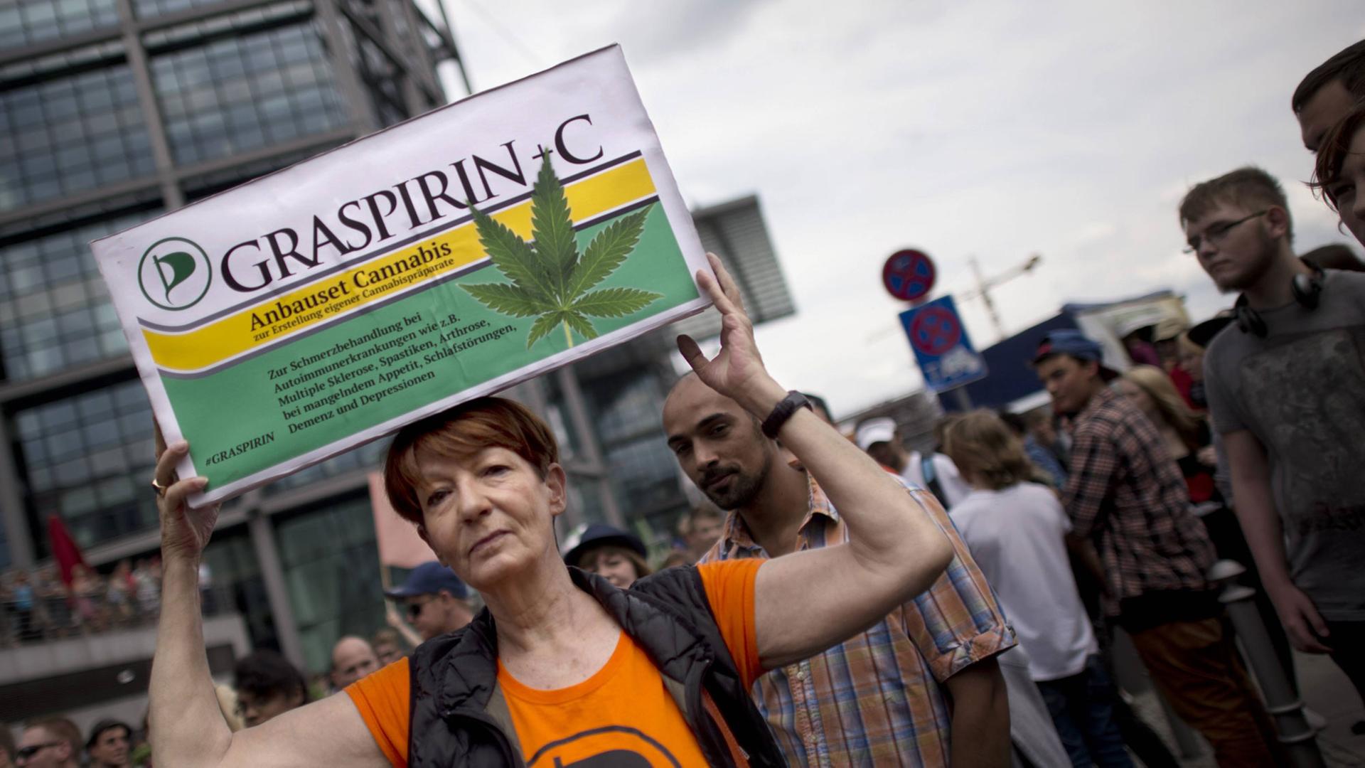 Teilnehmerin der Demonstration "Hanfparade" (Berlin) hält ein Plakat hoch, das einer Aspirin-Schachtel nachgeahmt ist.