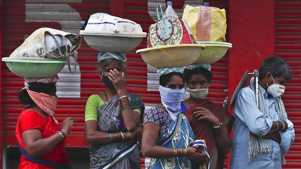 Indien, Hyderabad: Tagelöhnerinnen warten während des coronabedingten Lockdowns auf einem Gehweg auf eine Transportmöglichkeit. Indien, Hyderabad: Tagelöhnerinnen warten während des coronabedingten Lockdowns auf einem Gehweg auf eine Transportmöglichkeit.