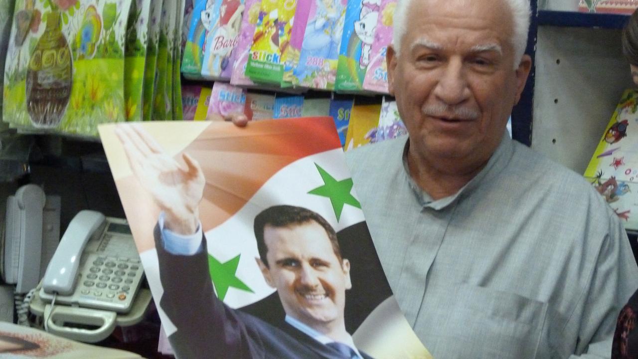 Ein Mann in Damaskus verkauft Flaggen mit Assad-Portrait. Ein Mann in Damaskus verkauft Flaggen mit Assad-Portrait.