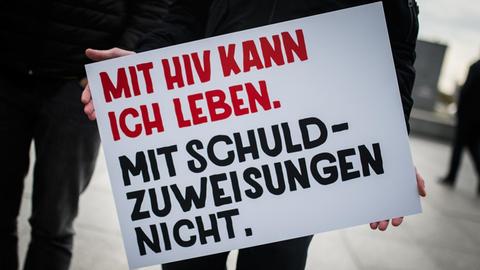 Ein Mann hält am 26.10.2017 in Berlin ein Plakat mit der Aufschrift "Mit HIV kann ich leben. Mit Schuldzuweisungen nicht." in den Händen. Im Rahmen der Welt-Aids-Kampagne wurden neue Plakat-Motive vorgestellt.