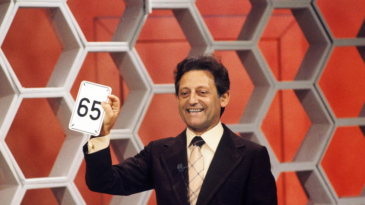 Der beliebte Quizmaster Hans Rosenthal während einer "Dalli-Dalli"-Sendung mit einer Karte in der Hand, auf der die Nummer "65" steht.