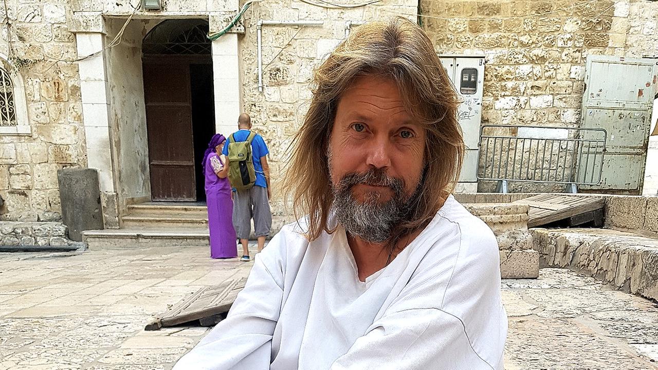 Der Amerikaner James Joseph, gekleidet wie Jesus Christus in einem weißen Gewand, mit Bart und langem blondem Haar, sitzt auf einer Steintreppe in der Nähe der Klagemauer in Jerusalem.