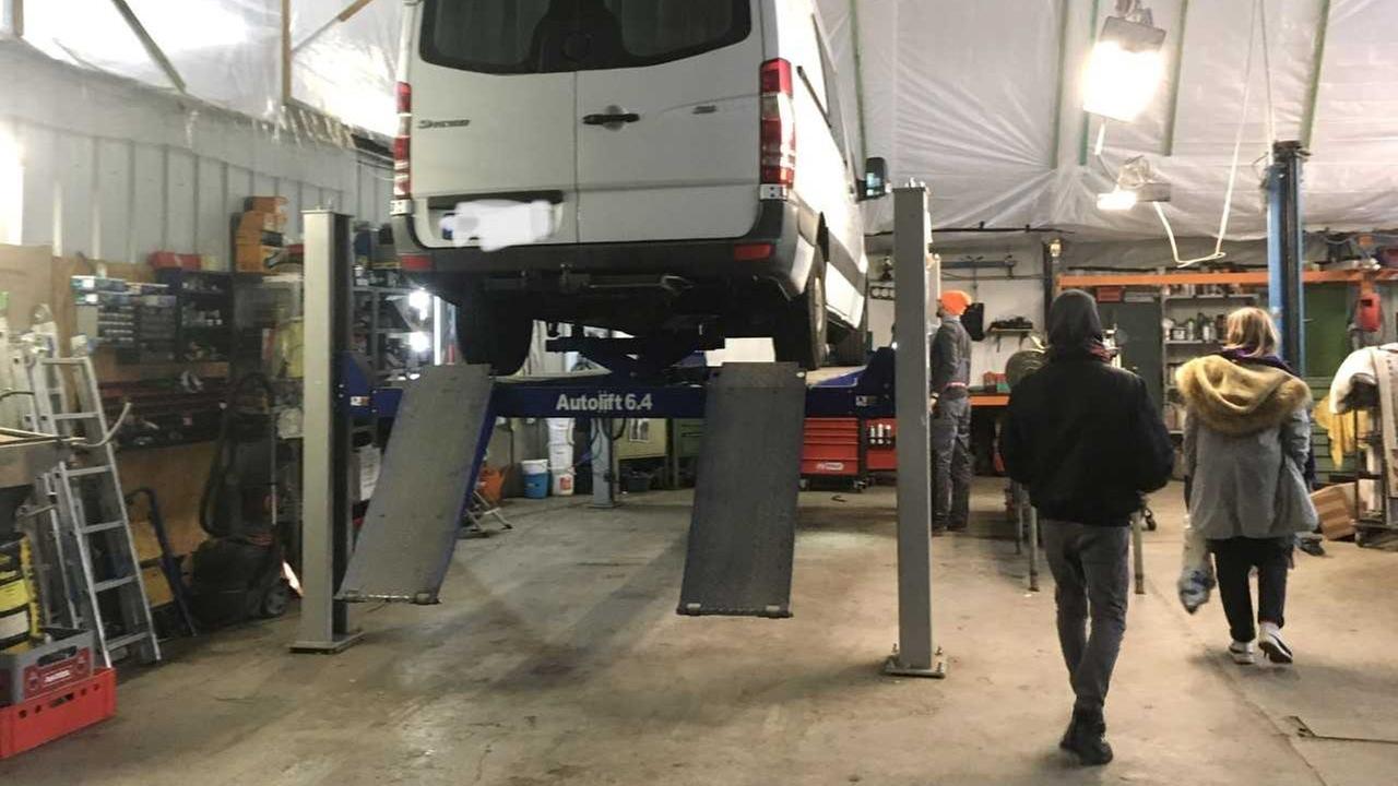 Ein weißer Lieferwagen steht in einer Werkstatt auf einer Hebebühne. Ein weißer Lieferwagen steht in einer Werkstatt auf einer Hebebühne.