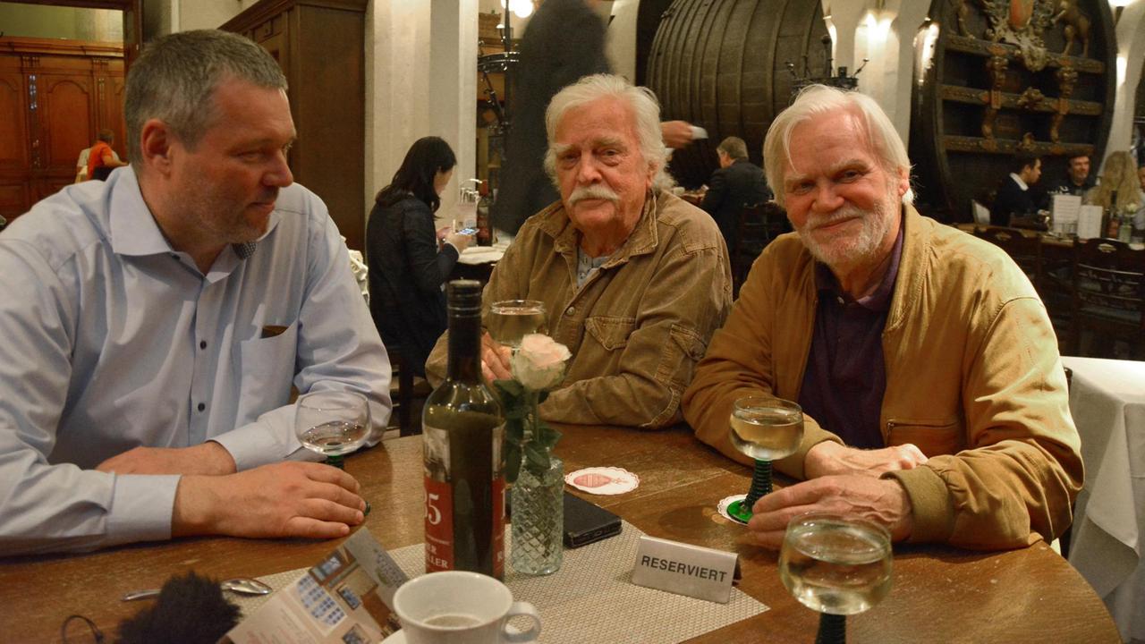 Drei Herren sitzen im Ratskeller in Bremen an einem Tisch mit der Aufschrift "Stammtisch". Sie trinken Weißwein.