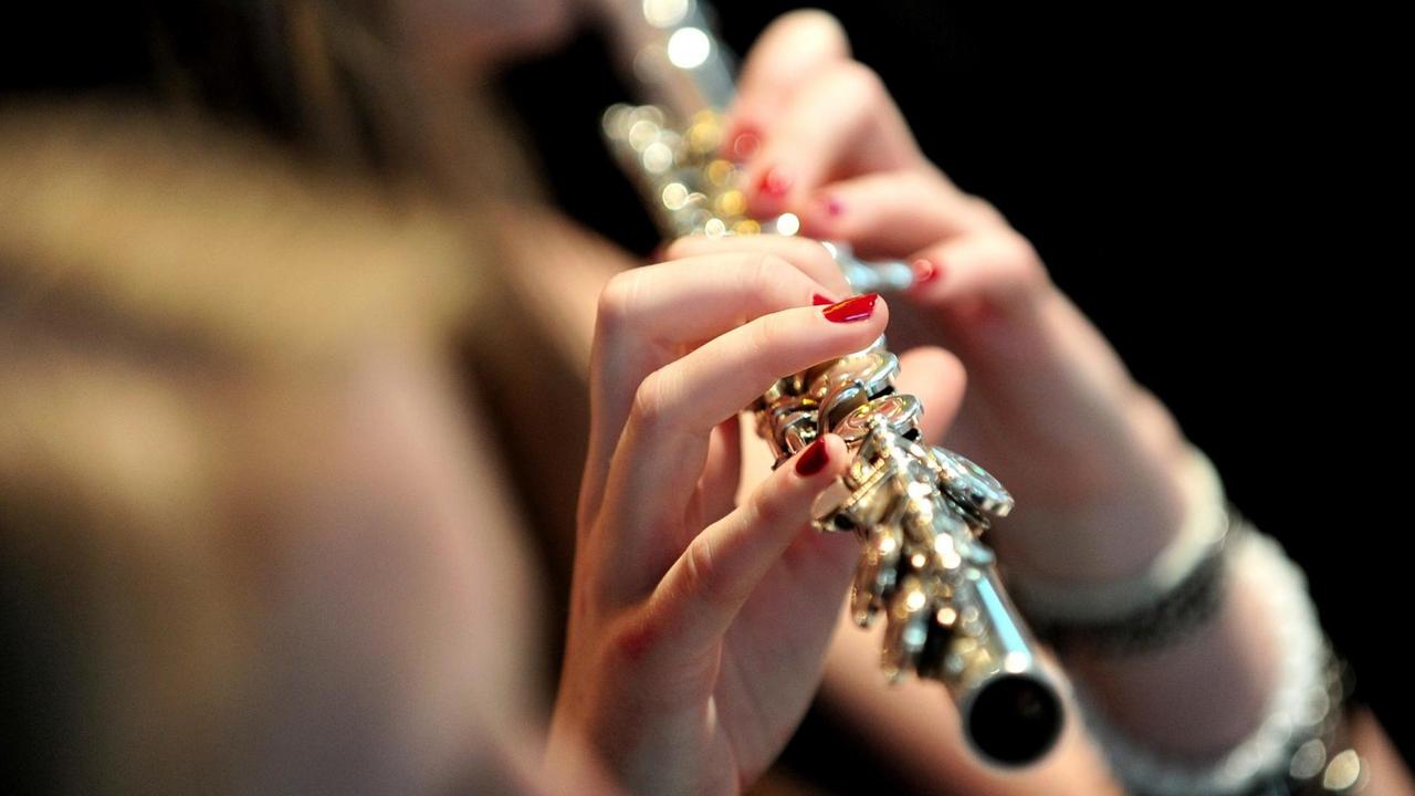 Eine junge Frau spielt eine Querflöte. Eine junge Frau spielt eine Querflöte.
