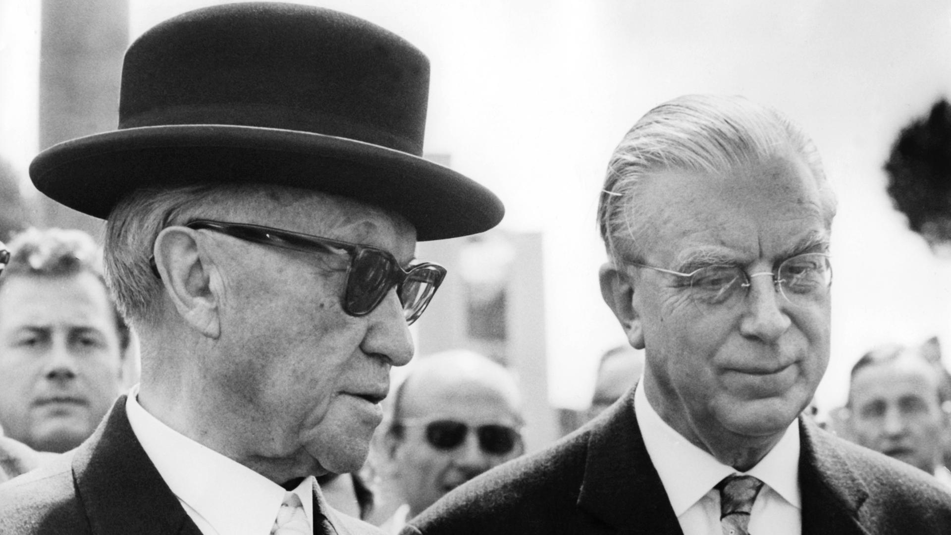 Kanzler Konrad Adenauer trägt eine Sonnenbrille und einen schwarzen Hut, rechts neben ihm steht Kanzleramtschef Hans Globke Kanzler Konrad Adenauer trägt eine Sonnenbrille und einen schwarzen Hut, rechts neben ihm steht Kanzleramtschef Hans Globke
