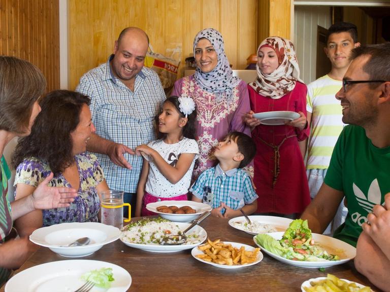 Der Syrer Walid Al Ali (3. v. l.) spricht am 03.08.2016 in Mangolding (Bayern) neben seiner Familie mit Helfern. Der 38-Jährige ist glücklich mit dem Dorfleben in der Oberpfalz.