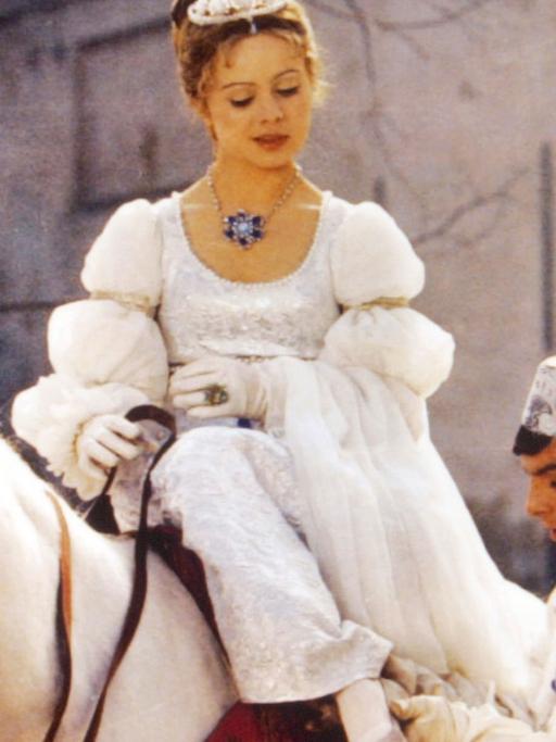 Szene aus dem Film "Drei Haselnüsse für Aschenbrödel": Der Prinz passt Aschenbrödel den verlorenen Schuh an. Sie sitzt dabei auf einem weißen Pferd und blickt zu ihm hinunter.