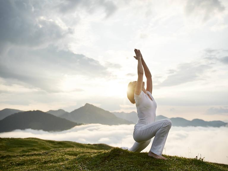 Yoga: Eine Frau macht den Sonnengruß gen Himmel.