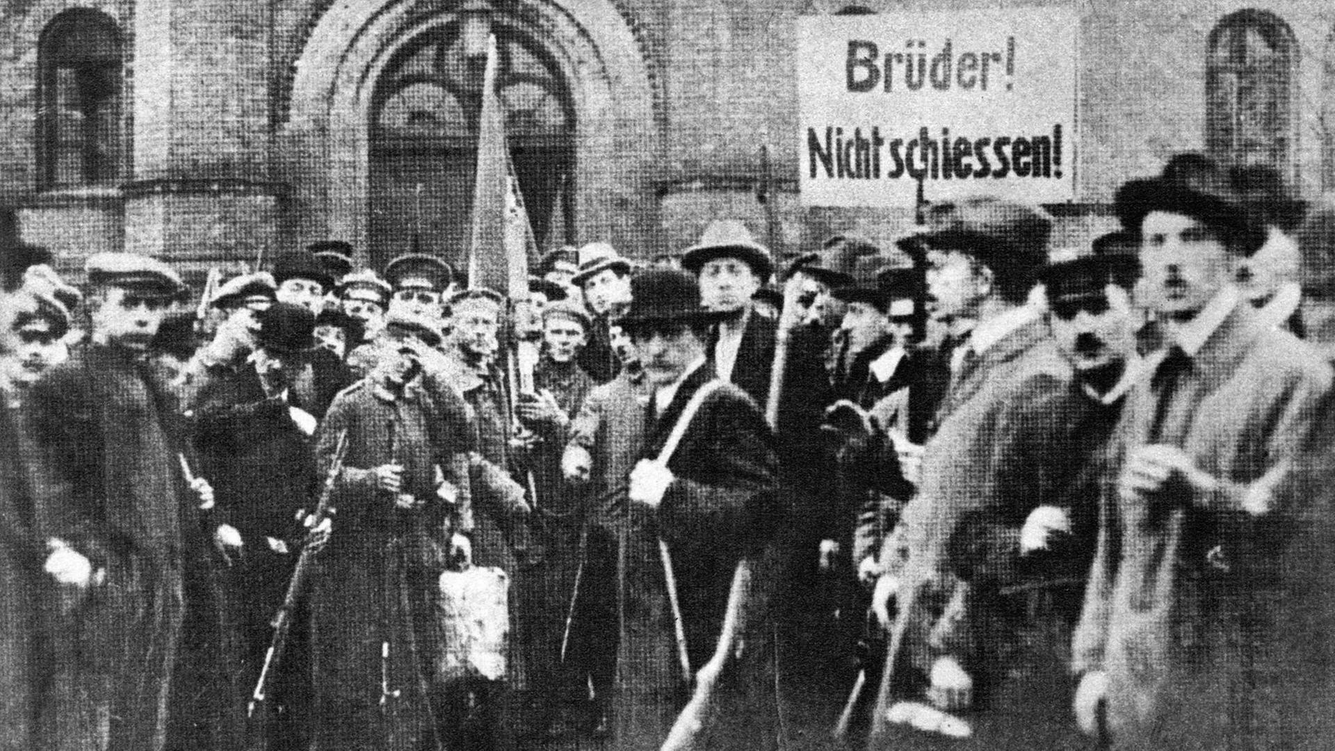 Soldaten und bewaffnete Personen in einer Straße in Berlin. Auf einem Plakat steht "Brüder! Nicht schießen!". Soldaten und bewaffnete Personen in einer Straße in Berlin. Auf einem Plakat steht "Brüder! Nicht schießen!".