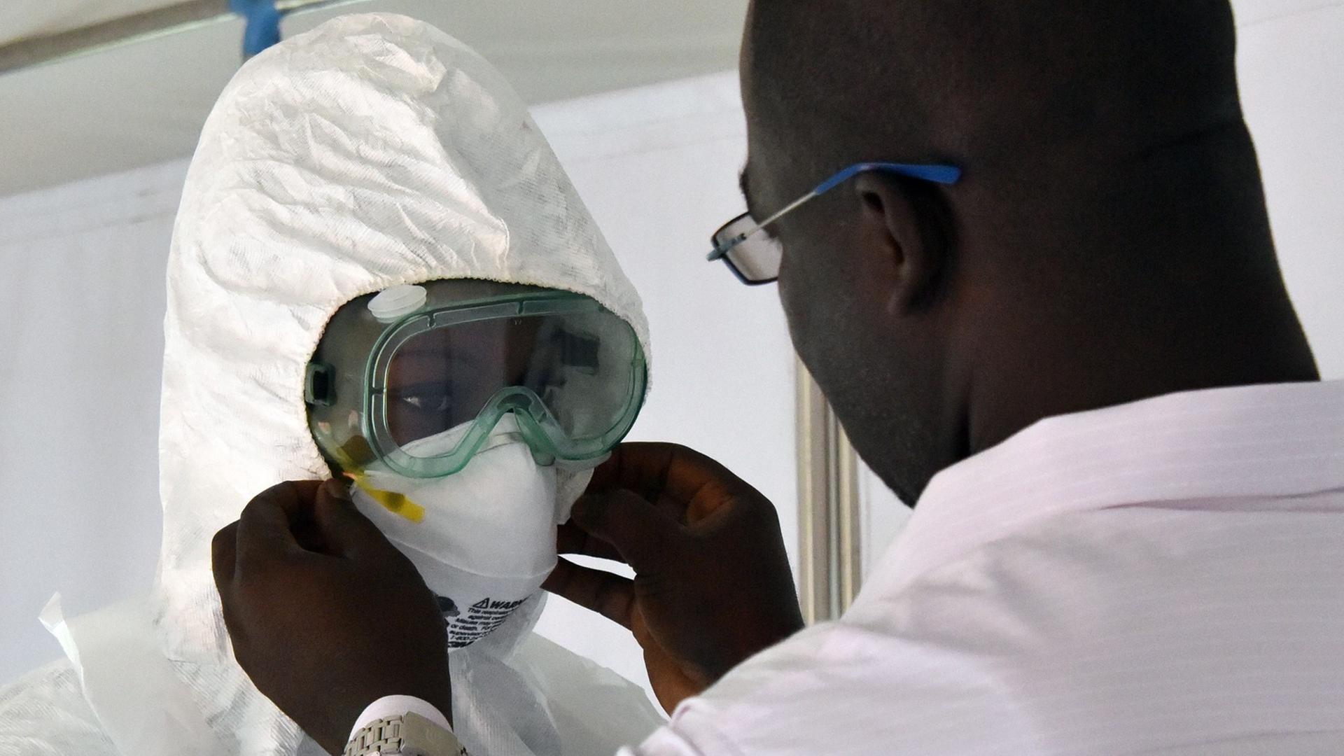 Ein afrikanischer Arzt hilft seinem Kollegen, dessen Atemschutzmaske anzupassen.