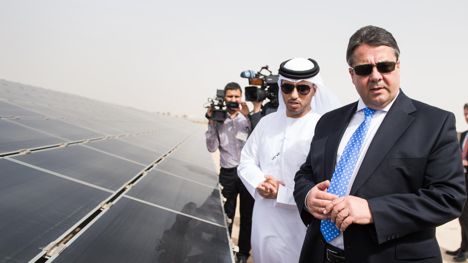 Bundeswirtschaftsminister Sigmar Gabriel, Sonnenbrille tragend, mit Ahmad Belhoul, dem Geschäftsführer des Masdar-Projekts, neben einem Solarfeld stehend. Bundeswirtschaftsminister Sigmar Gabriel, Sonnenbrille tragend, mit Ahmad Belhoul, dem Geschäftsführer des Masdar-Projekts, neben einem Solarfeld stehend.